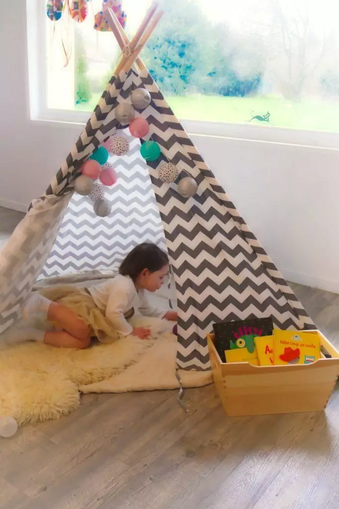 Une enfant joue sous un tipi dans la salle de jeux